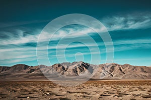 A harsh, solitary desert with jagged peaks under a vast blue sky.