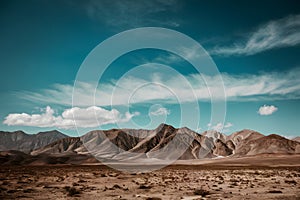 A harsh, solitary desert with jagged peaks under a vast blue sky.