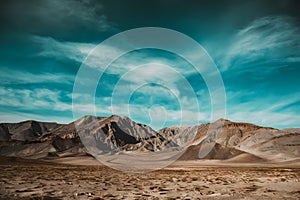 A harsh, solitary desert with jagged peaks under a vast blue sky.