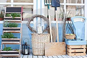 Harvest concept. Wicker baskets next to garden equipment by the wall of a blue country house. The decor of the courtyard of a cou