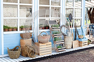 Harvest concept. Wicker baskets next to garden equipment by the wall of a blue country house. The decor of the courtyard of a coun