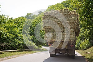 After the harvest. Early autumn. The truck is carrying hay. hay carrier at the interurban road . The truck carries rolls of hay