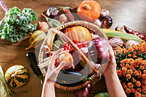 Harvest: female hand putting vegetables in wicker basket