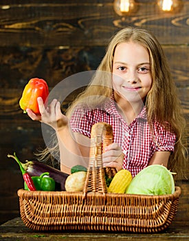 Harvest festival concept. Kid girl near basket full of fresh vegetables harvest rustic style. Farm market fall harvest