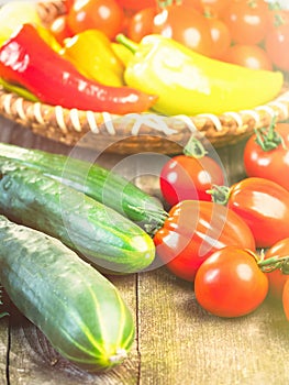 Harvest of fresh ripe vegetables on wooden table and in rod bowl - pepper, tomato, cucumber.