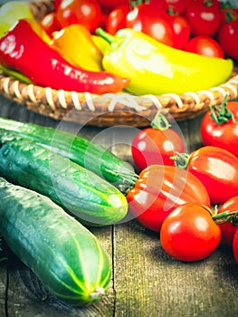 Harvest of fresh ripe vegetables on wooden table and in rod bowl - pepper, tomato, cucumber. photo