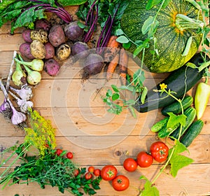 Harvest of fresh vegetables on wooden background. Top view. Potatoes, carrot, squash, peas, tomatoes