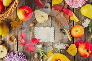 Harvest or Thanksgiving background with autumnal fruits, flowers, gourd and greeting card on a rustic wooden table. Autumn vintage