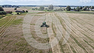 Harvest time. Combine harvester harvests barley in the field in summer day. Aerial view