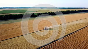 Harvest, tractor, wheat and eco concept. Aerial shot of harvester loading wheat on trailer. Modern tractor riding across