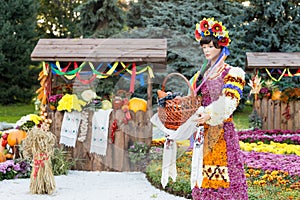 Harvest vegetables on fair trade in a wooden pavilion. Female mannequin holding basket full of fruits. Agricultural products