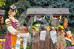 Harvest vegetables on fair trade in a wooden pavilion. Female mannequin holding basket full of fruits. Agricultural products