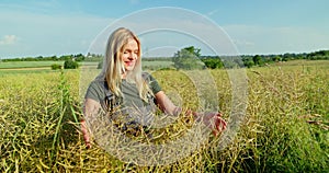 Harvest vigilance: portrait of a woman inspecting rapeseed crop in July