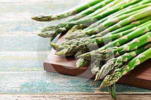 Harvest of young green asparagus sprouts on rural wooden table. Organic vegetarian food.