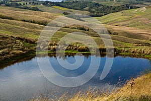 Harvested Fields and meadows landscape in Tuscany, Italy. Wavy country scenery at autumn sunset.