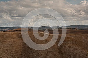 Harvested Fields and meadows landscape in Tuscany, Italy. Wavy country scenery at autumn sunset.