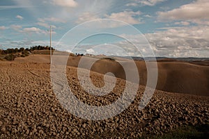 Harvested Fields and meadows landscape in Tuscany, Italy. Wavy country scenery at autumn sunset.