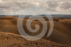 Harvested Fields and meadows landscape in Tuscany, Italy. Wavy country scenery at autumn sunset.