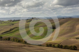 Harvested Fields and meadows landscape in Tuscany, Italy. Wavy country scenery at autumn sunset.