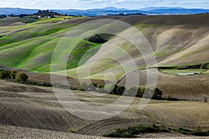 Harvested Fields and meadows landscape in Tuscany, Italy. Wavy country scenery at autumn sunset.