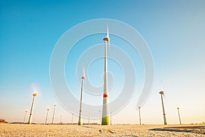 Harvested wheat field with turning windmill turbines