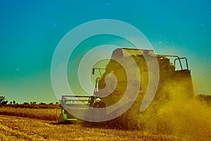 Harvester combine harvesting wheat on summer day
