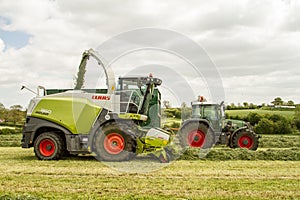 Harvester cutting field, loading Silage into a Tractor Trailer