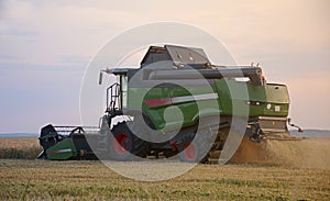 Harvester harvests wheat in the field at sunset closeup. Agriculture banner concept