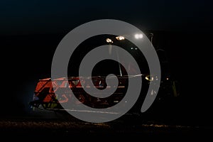 Harvester at work on field at night