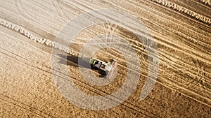 Harvester working in field and mows wheat. Ukraine. Aerial view.