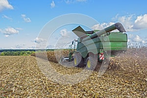 Harvesting corn by a combine harvester, followed by unloading and transportation of grain. Work in the field in the rays of the su