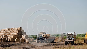 Harvesting hay. Tractor loading hay bales on a trailer. Pressing straw into ricks by baler. Transportation of pressed