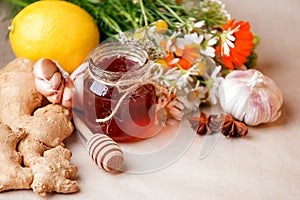 Harvesting herbs, flower garlic, lemon, ginger root, honey in jar - concept of seasonal winter autumn fall days, beverage for cold