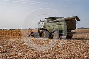 Harvesting ripe dry corn in the field with a green harvester