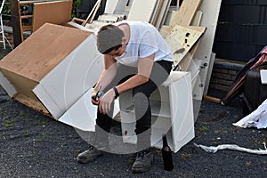 After he has done his  work teenage boy sits  in the bulky refuse