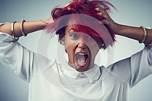 She has fire in her soul. Studio shot of an attractive young woman screaming against a gray background.