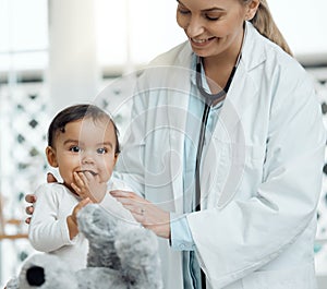 She has her teddy to bring her comfort. Shot of a paediatrician examining a baby in a clinic.