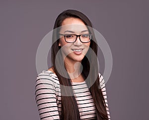 She has looks and brains. Studio shot of a casually dressed woman against a gray background.