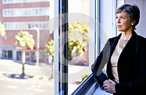 She has the mindset for success. a thoughtful businesswoman looking out of an office window.