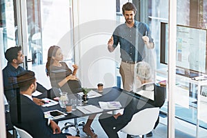 He has some innovative ideas. High angle shot of a young businessman giving a presentation in the boardroom.