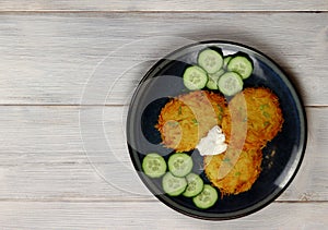 Hashbrowns on a plate on a light wooden background. Served with sour cream. Top view