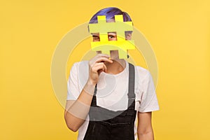 Hashtag, interesting media trends. Portrait of cheerful young woman looking at camera through big hash sign with curious eyes.