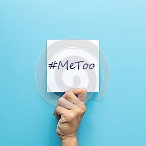 Hashtag  MeToo on white paper in hand isolated on blue background.  MeToo is a campaign for movement against sexual harassment photo