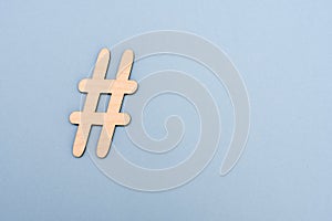 Hashtag sign made of wooden material on blue background