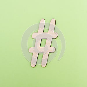 Hashtag sign made of wooden material on green background