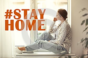 Hashtag Stayhome - protective measure during coronavirus pandemic. Young woman sitting on window sill indoors