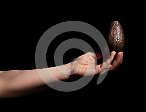 hass avocado in hand on black photo