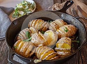 Hasselback potatoes with butter and cheese in a cast ironpan