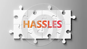 Hassles complex like a puzzle - pictured as word Hassles on a puzzle pieces to show that Hassles can be difficult and needs photo