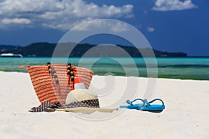 Hat, bag, sun glasses and flip flops on tropical beach